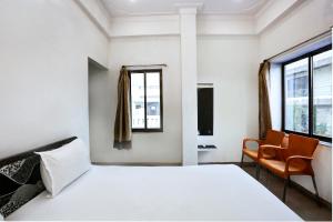 um quarto branco com uma cama e uma cadeira em Super OYO Hotel Goverdhan Villa em Udaipur