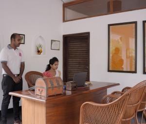 a man and a woman standing next to a desk with a laptop at Kanan Beach Resort in Nīleshwar