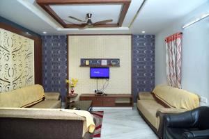 een woonkamer met 2 banken en een tv bij S.V Guest House in Pedda Ambarpet