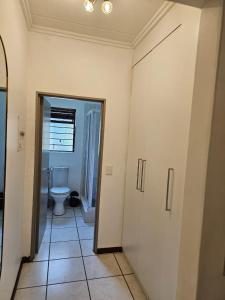 a bathroom with a toilet and a hallway with a door at Premium Apartment In Fourways in Sandton