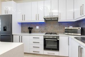 uma cozinha com armários brancos e um forno com placa de fogão em Shanthi Apartment 8 em Ballito