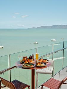 einen Tisch mit Speisen und Getränken auf einem Balkon mit Meerblick in der Unterkunft Ardo in Townsville