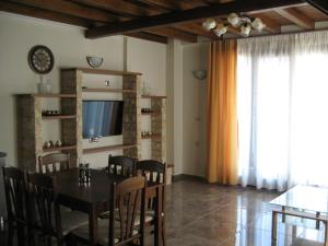 una sala da pranzo con tavolo, sedie e TV di Alexander D.J.K. Apartments a Ierissós