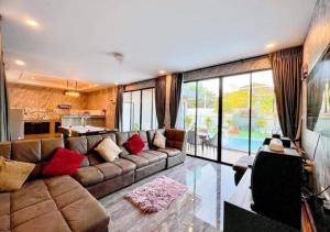 a living room with a large couch and a kitchen at Por House99 poolvilla in Hua Hin
