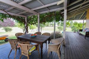 a wooden table and chairs on a porch at Reset your Senses in Meroo at Lone Pine Farmhouse in Windeyer