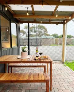 un patio con una mesa de madera y un banco en The Shack @ Port Elliot, en Port Elliot