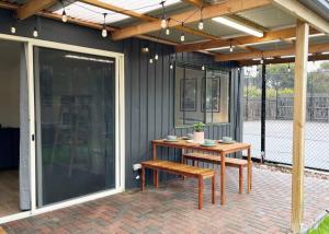 un patio con una mesa de madera y un banco en The Shack @ Port Elliot, en Port Elliot