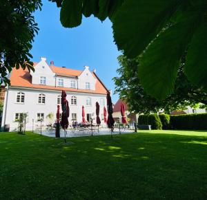 un gran edificio blanco con sombrillas rojas en el césped en Gasthof Rössle Eberhardzell, en Füramoos