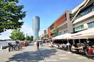 Skala Waterfront - Beograd na vodi في بلغراد: شارع فيه ناس جالسين على طاولات ومبنى