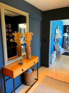 ein Zimmer mit einem Spiegel und einem Tisch mit Blumen darauf in der Unterkunft Appartement spacieux, calme et lumineux. in Caen