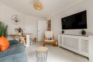 uma sala de estar com um sofá azul e uma televisão de ecrã plano em Modern, comfy Town centre gem, near beach, parking em Bournemouth