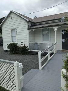 a house with a white fence in front of it at Wharf Road Cottage in Coromandel Town