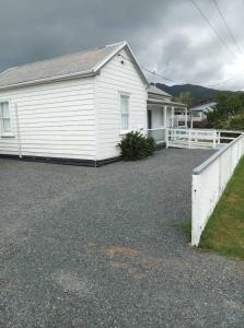a white house with a white fence in front of it at Wharf Road Cottage in Coromandel Town
