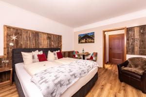 a bedroom with a large bed and a chair at Alpenhotel Bergzauber in Berchtesgaden