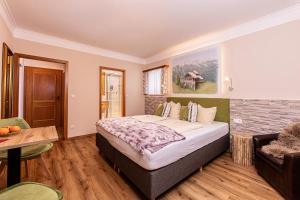 1 dormitorio con cama, mesa y sofá en Alpenhotel Bergzauber en Berchtesgaden