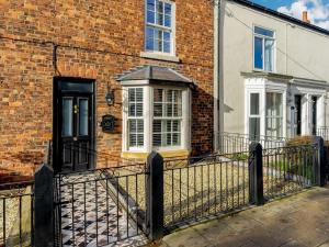 a brick house with a black door and a fence at 3 Bed House With Hot Tub Great Ayton - TOP Terrace in Great Ayton
