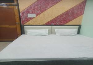 uma cama branca com duas almofadas num quarto em Dev Aagmann In em Ayodhya