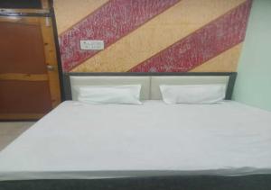 a white bed with two pillows in a room at Dev Aagmann In in Ayodhya