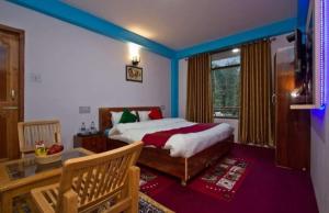 una camera con letto in una stanza con soffitti blu di Hotel Royal Orbit a Manāli
