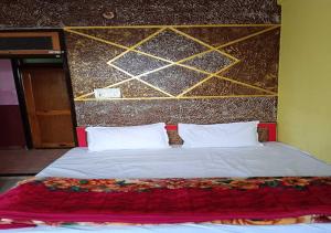 um quarto com uma cama grande e almofadas brancas em Dev Aagmann In em Ayodhya