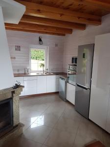 a kitchen with white cabinets and a refrigerator and a window at Wakacyjny Hartowiec - dom nad brzegiem jeziora in Grodziczno