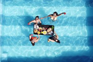 eine Gruppe von Personen in einem Pool mit einem Tablett mit Essen in der Unterkunft Elivaas Opalys Luxe 4BHK Villa with Pvt Pool near Baga in Calangute