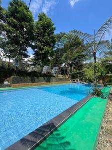 uma grande piscina azul com árvores ao fundo em Villa Kolah Watu em Wonosobo