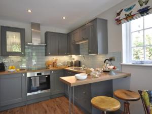 een keuken met grijze kasten en een aanrecht met krukken bij 1 Bed in Upper Brailes 57103 in Upper Brailes