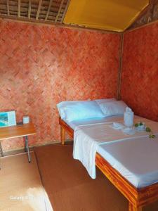 a small bedroom with a bed and a table at Kubo Inn & Beach Camp in El Nido