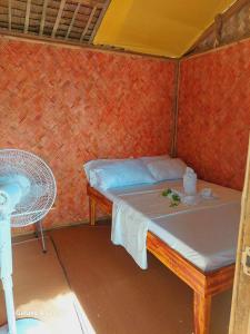 Habitación pequeña con cama y silla en Kubo Inn & Beach Camp en El Nido