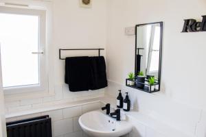 ein weißes Badezimmer mit einem Waschbecken und einem Spiegel in der Unterkunft Stunning 1-Bedroom House in Crystal Palace London in London