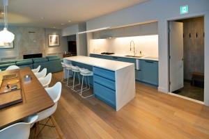 a kitchen and living room with blue cabinets and a table at Shirokuma Chalets in Kutchan