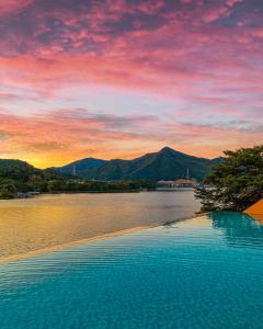 a swimming pool with a view of a lake at sunset at Gapyeong Suiteian Hotel&Resort in Gapyeong