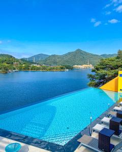 a large swimming pool with chairs and a lake at Gapyeong Suiteian Hotel&Resort in Gapyeong