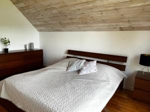 a bedroom with a white bed with a wooden ceiling at Wakacyjny Hartowiec 2 in Grodziczno