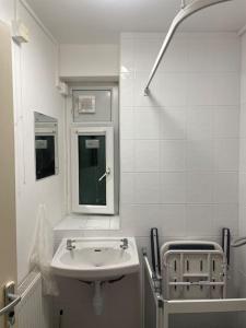 a white bathroom with a sink and a mirror at Cosy 1 bedroom flat… in London