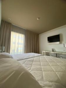 una camera da letto con un grande letto bianco e una televisione di One Hotel & Restaurant a Dalmine