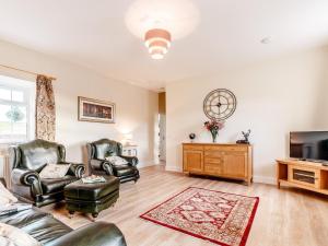 a living room with two leather chairs and a television at 2 Bed in Kirriemuir 80719 in Pearsie