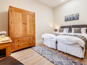a bedroom with two beds and a wooden dresser at 2 Bed in Kirriemuir 80719 in Pearsie