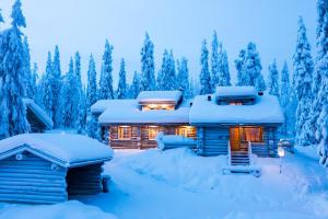 eine Blockhütte im Schnee mit eingeschaltetem Licht in der Unterkunft Kuusirinne 2B -A cozy cabin near the slopes of Ruka in Ruka
