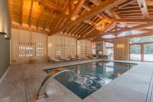 a swimming pool in a house with a wooden ceiling at Chalet Eden Eco Hotel, Restaurant & Wellness in La Thuile