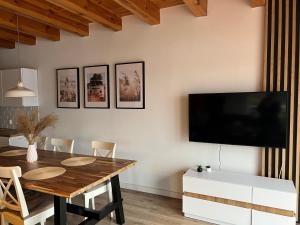 a dining room with a table and a tv on the wall at Wakacyjny Hartowiec 2 in Grodziczno
