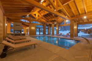 an indoor swimming pool in a house with wooden ceilings at Chalet Eden Eco Hotel, Restaurant & Wellness in La Thuile