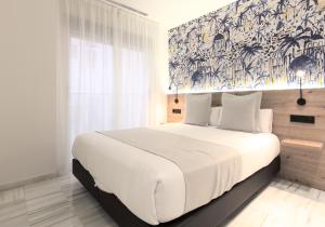 a bedroom with a large white bed with a painting on the wall at Hotel La Milagrosa in Alicante