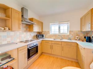 eine Küche mit Holzschränken, einer Spüle und einer Mikrowelle in der Unterkunft 2 Bed in Shanklin IC004 in Shanklin