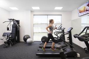 a woman running on a treadmill in a gym at Mercure Newcastle Airport in Newcastle