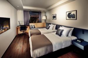 a hotel room with two beds and a desk at Ramada by Wyndham Gunsan in Gunsan-si