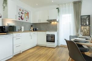 uma cozinha com armários brancos e uma mesa de jantar em Ferienwohnung mit Terrasse - Erdgeschoss em Weilburg