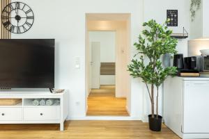 a living room with a flat screen tv and a plant at Ferienwohnung mit Terrasse - Erdgeschoss in Weilburg