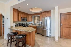 a kitchen with wooden cabinets and a stainless steel refrigerator at Entire Beachfront condo in Paradise in San José del Cabo